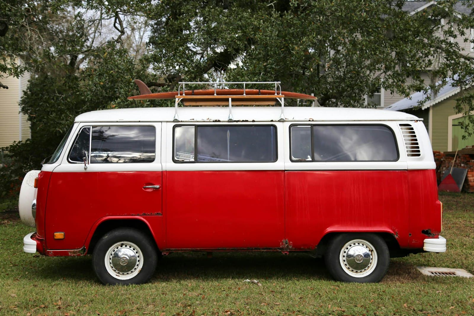 Combi Volkswagen vintage rouge et blanc avec planche de surf sur la galerie
